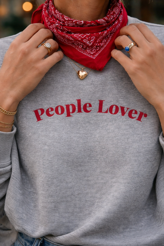 Person wearing a gray sweatshirt with 'People Lover' text and a red bandana, blurred background